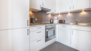 Una cocina moderna con armarios blancos, electrodomésticos de acero inoxidable e iluminación debajo de los gabinetes.