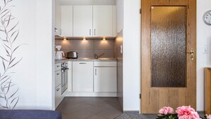 Una cocina moderna con armarios blancos, una puerta de madera y un reloj en la pared.