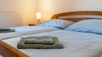 Ein Doppelbett mit Holz-Kopfteil, zwei Kissen, einer Nachttischlampe und gefalteten Handtüchern auf dem Bett.
