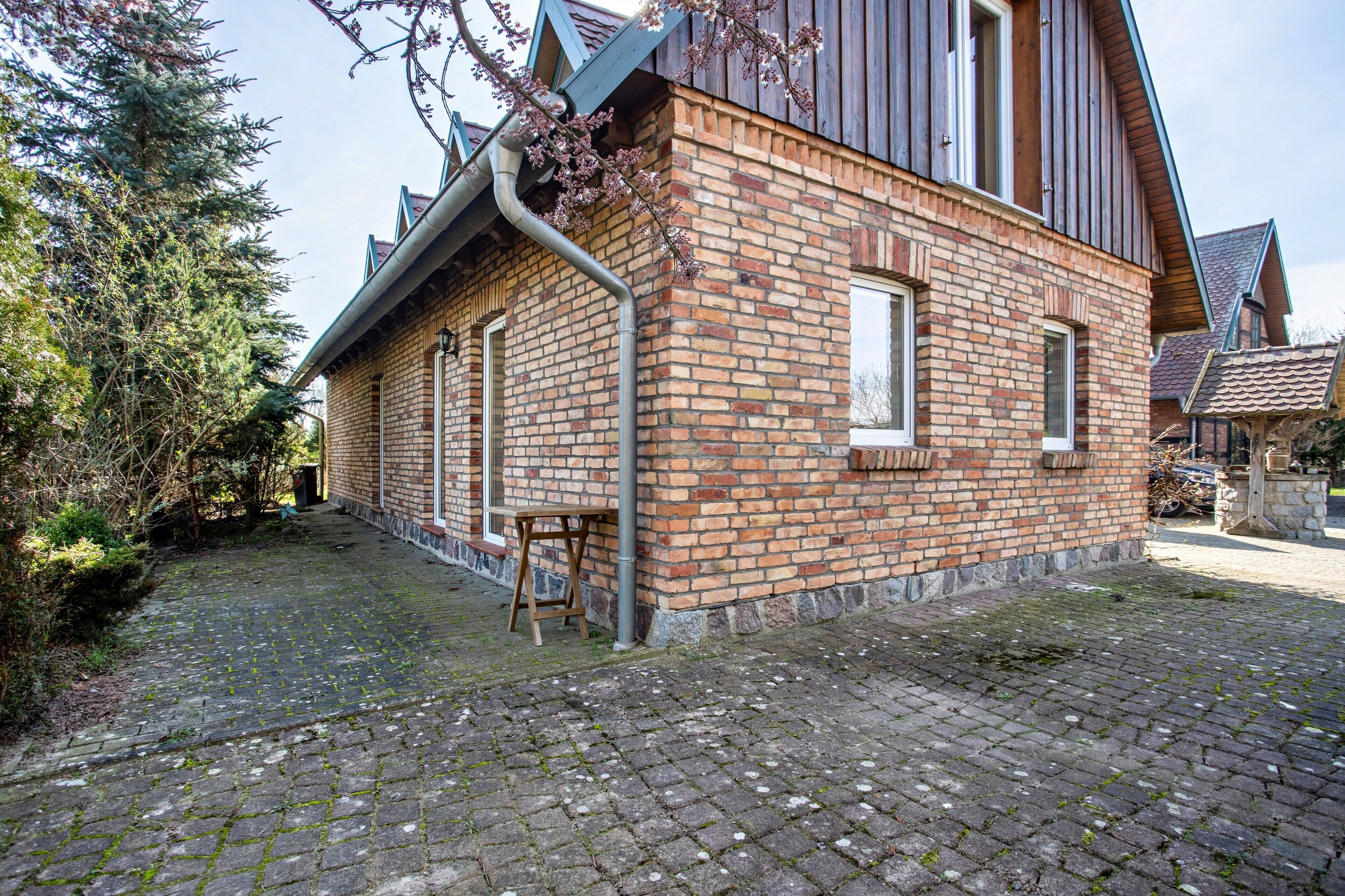 A brick building with a sloped roof, a wooden door, and a brick wall.