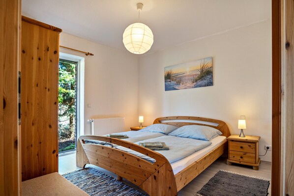 Une chambre à coucher avec un lit en bois, des tables de chevet, un luminaire suspendu et un tableau au mur.