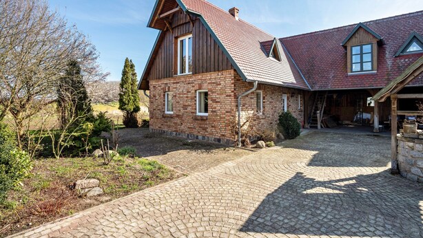 A two-story house with a brick facade, a sloped roof, and a paved driveway. - Apartment 'Hof Verchen Nahe Kummerower See' with Private Terrace, Private Garden and Wi-Fi (Verchen)