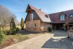 Une maison à deux étages avec une façade en briques, un toit en pente et une allée pavée.