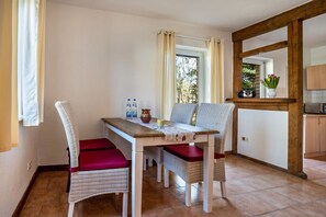 Un espace repas comprenant une table, des chaises et une vue par la fenêtre.