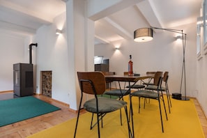 Een eethoek met een tafel, stoelen, een staande lamp en een open haard.