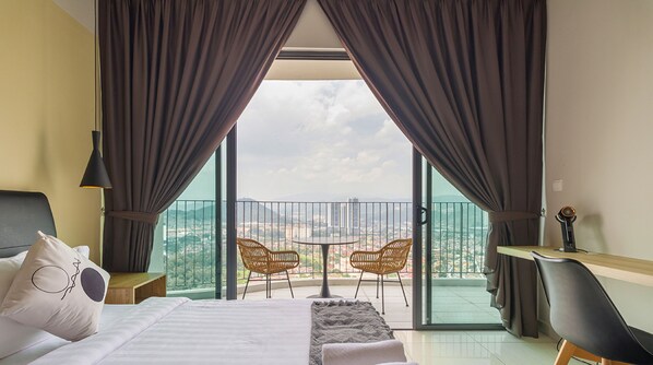 A hotel room with a bed, a desk, two chairs, and a balcony with a view of the city. - Datum Jelatek Sky Residence Roam (Ampang)