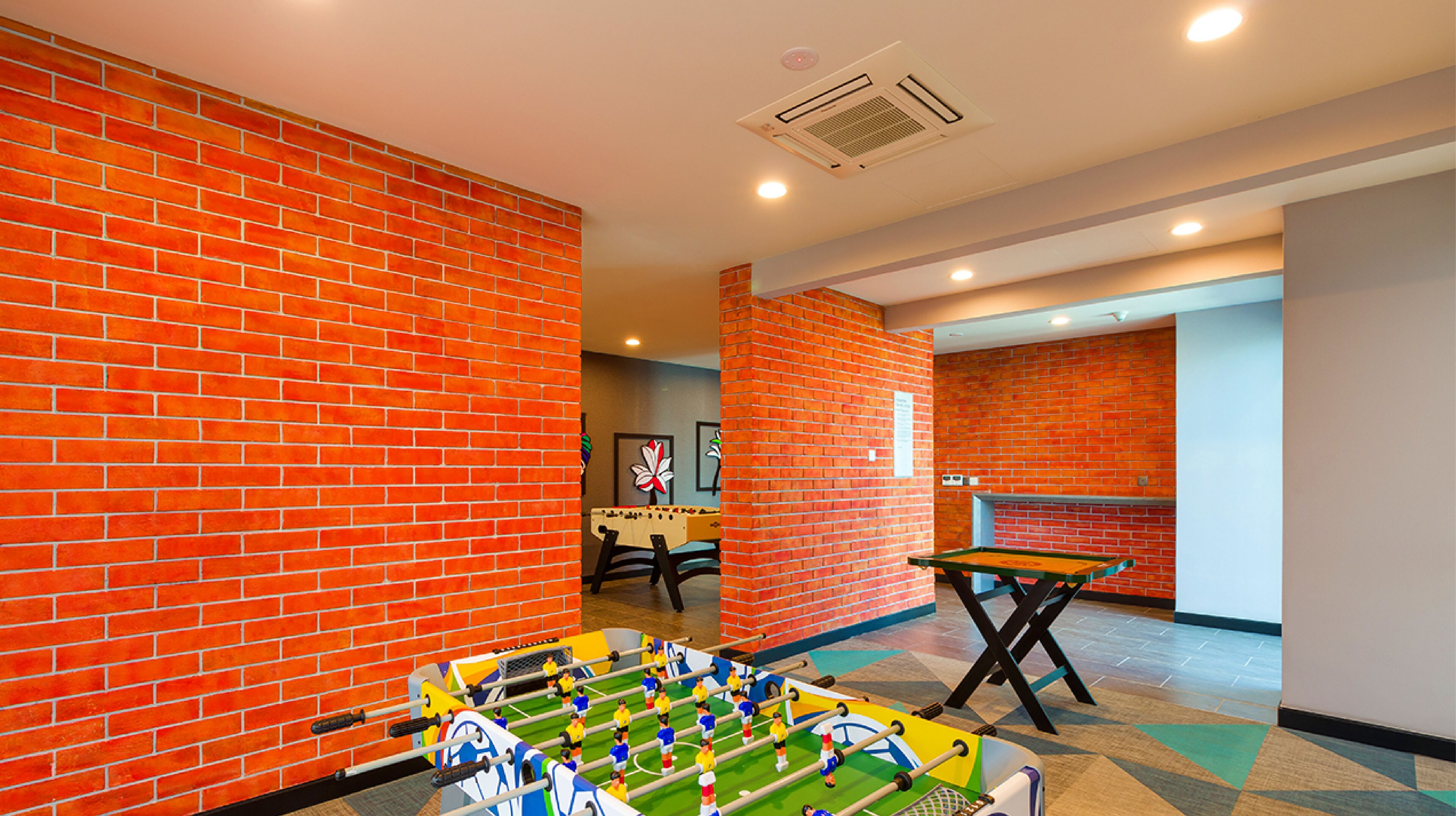 Een kamer met een tafelvoetbaltafel, een pooltafel en een bakstenen muur.