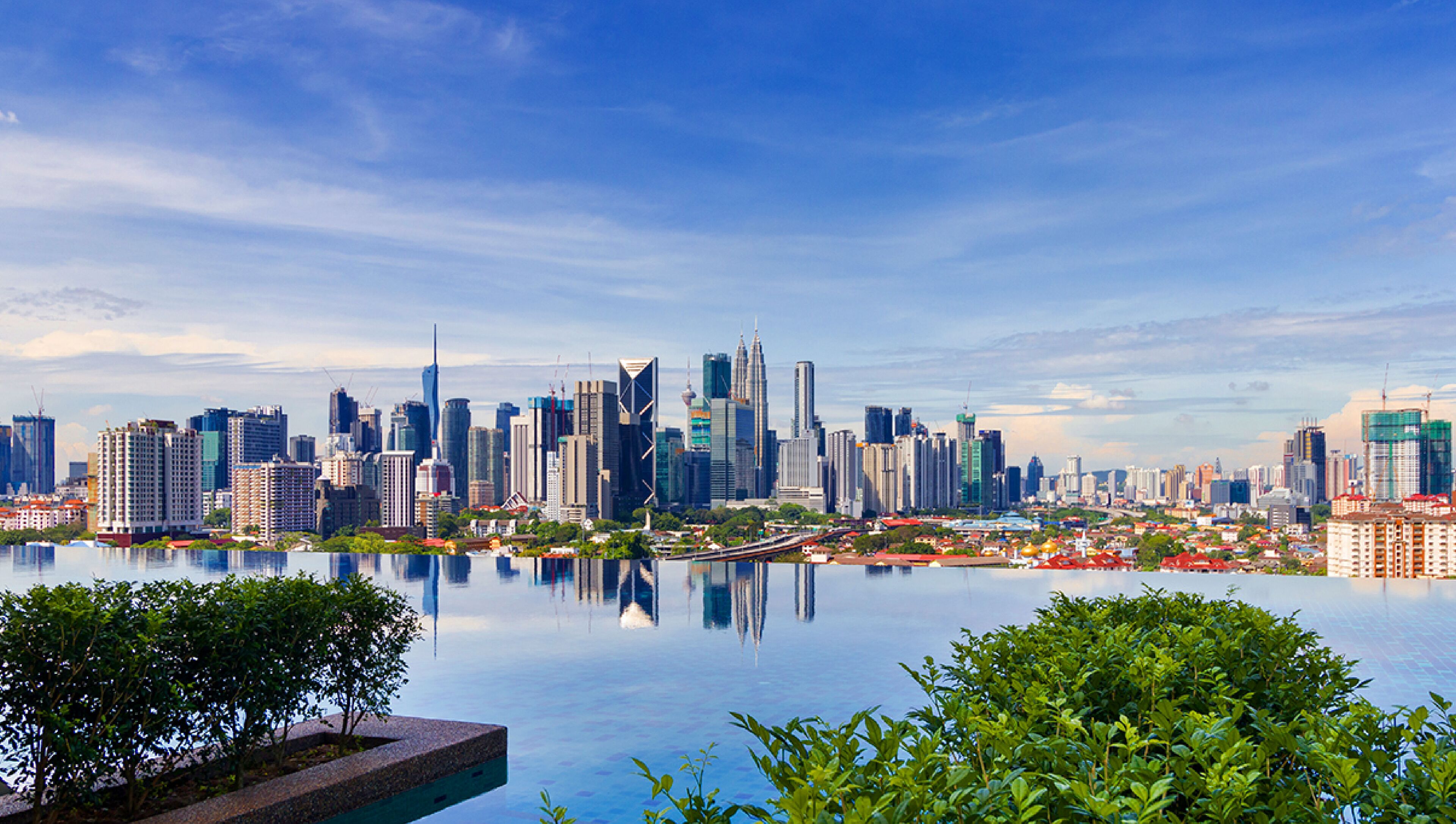 A city skyline with modern skyscrapers and a calm body of water reflecting the buildings.