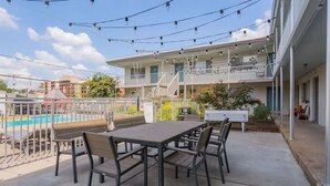 A poolside area with a table and chairs, a pool, and a building with balconies. - Near 12th South | Pool | 3 mi. to Broadway (Nashville)
