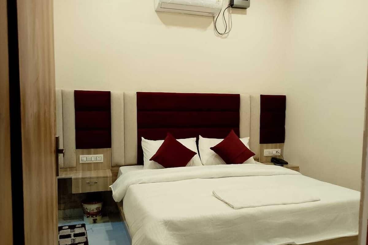 Una habitación de hotel con cama, mesita de noche y aire acondicionado instalado en la pared.