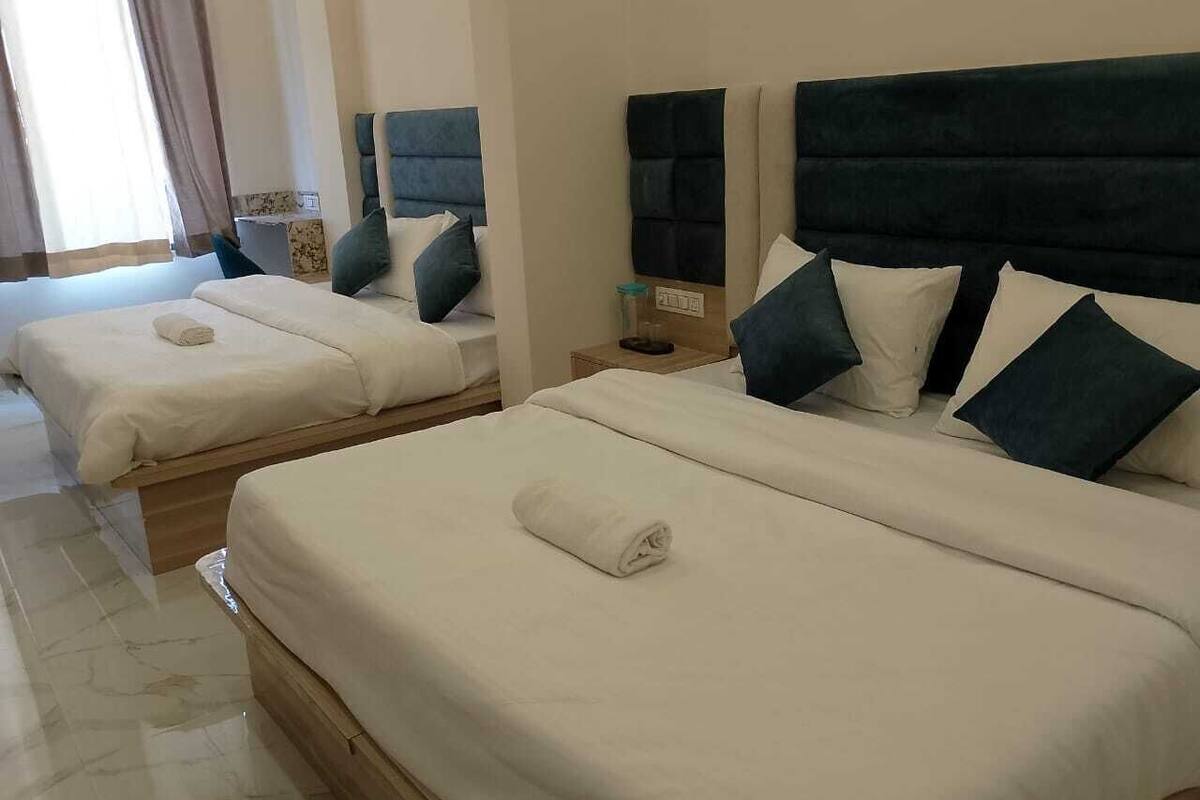 Una habitación de hotel con dos camas, cada una con cabecera, mesita de noche y una toalla enrollada sobre la cama.