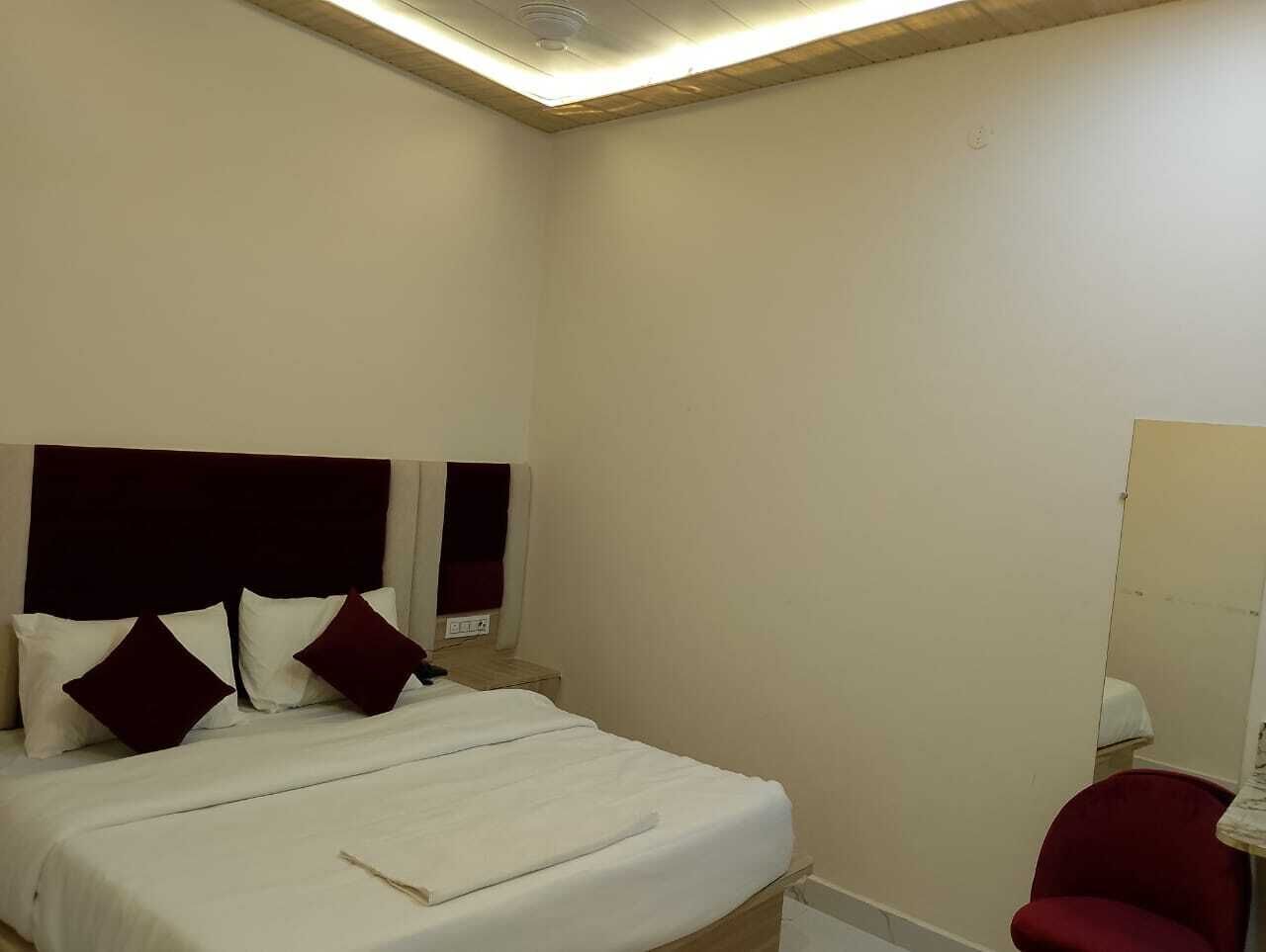 A hotel room with a bed, a red chair, and a mirror.