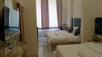 A hotel room with two beds, a television, a marble countertop, and a window with curtains.