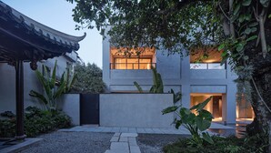 A modern building with a traditional roof, surrounded by lush greenery and a gravel pathway. - Jiangnan House Chaozhou (Chaozhou)
