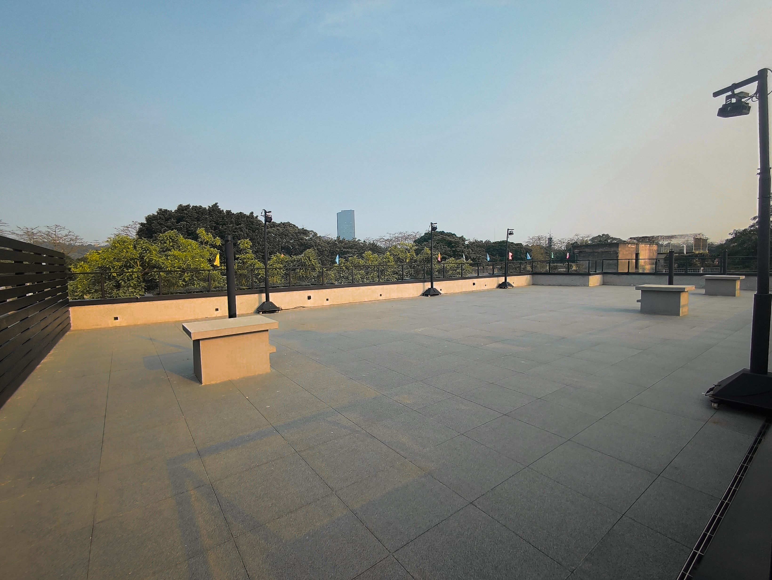 Una terraza abierta con suelo de baldosas, bancos y barandilla.