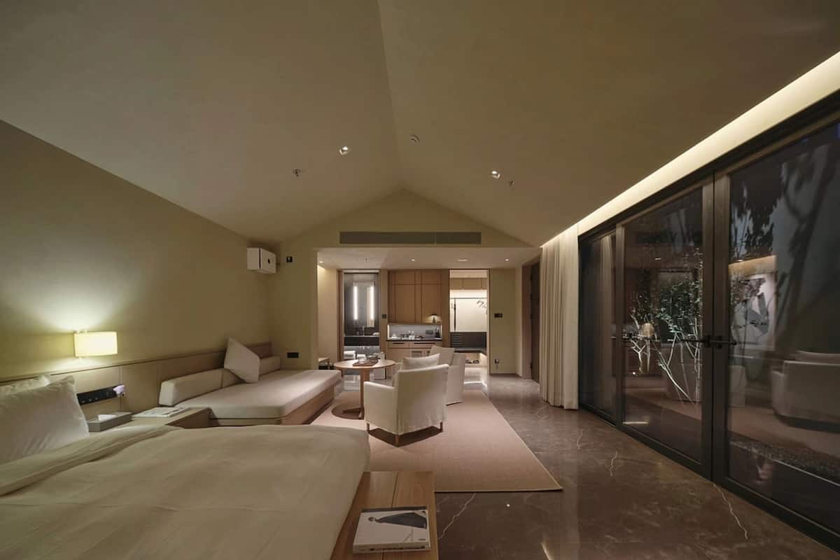 Une chambre d’hôtel moderne dotée d’un grand lit, d’un coin salon, d’une cuisine et d’un balcon avec vue.