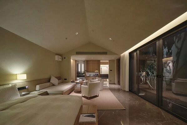 A modern hotel room with a large bed, a seating area, a kitchen, and a balcony with a view. - Jiangnan House Chaozhou (Chaozhou)