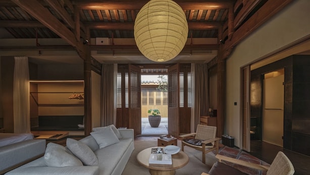 A traditional-style living room with a sofa, coffee table, and chairs, wooden beams, and a hanging lantern. - Jiangnan House Chaozhou (Chaozhou)
