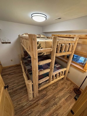 A bunk bed with a wooden frame, a window with a view, and a sign on the wall.