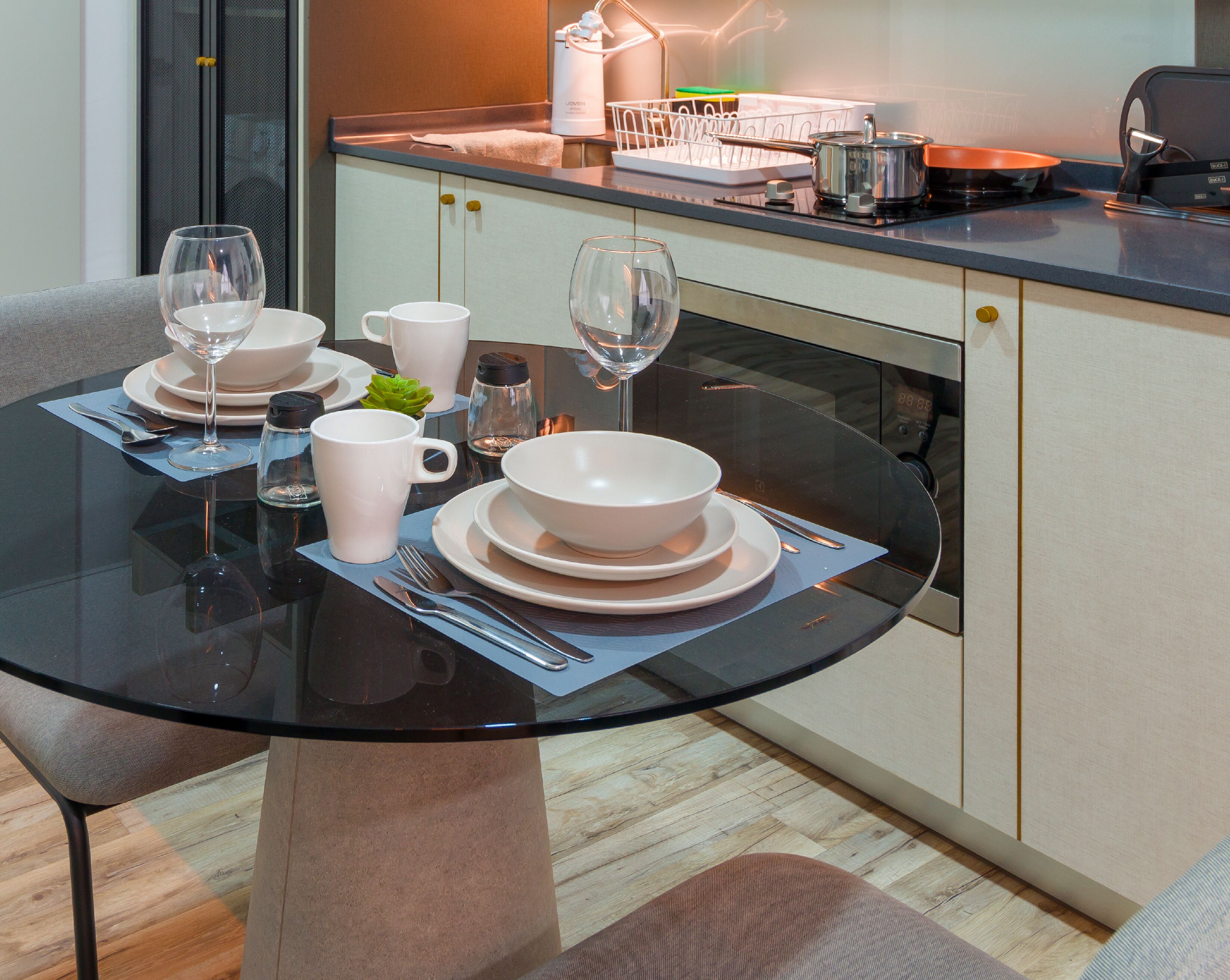 A modern kitchen with a glass dining table, white plates, and bowls.