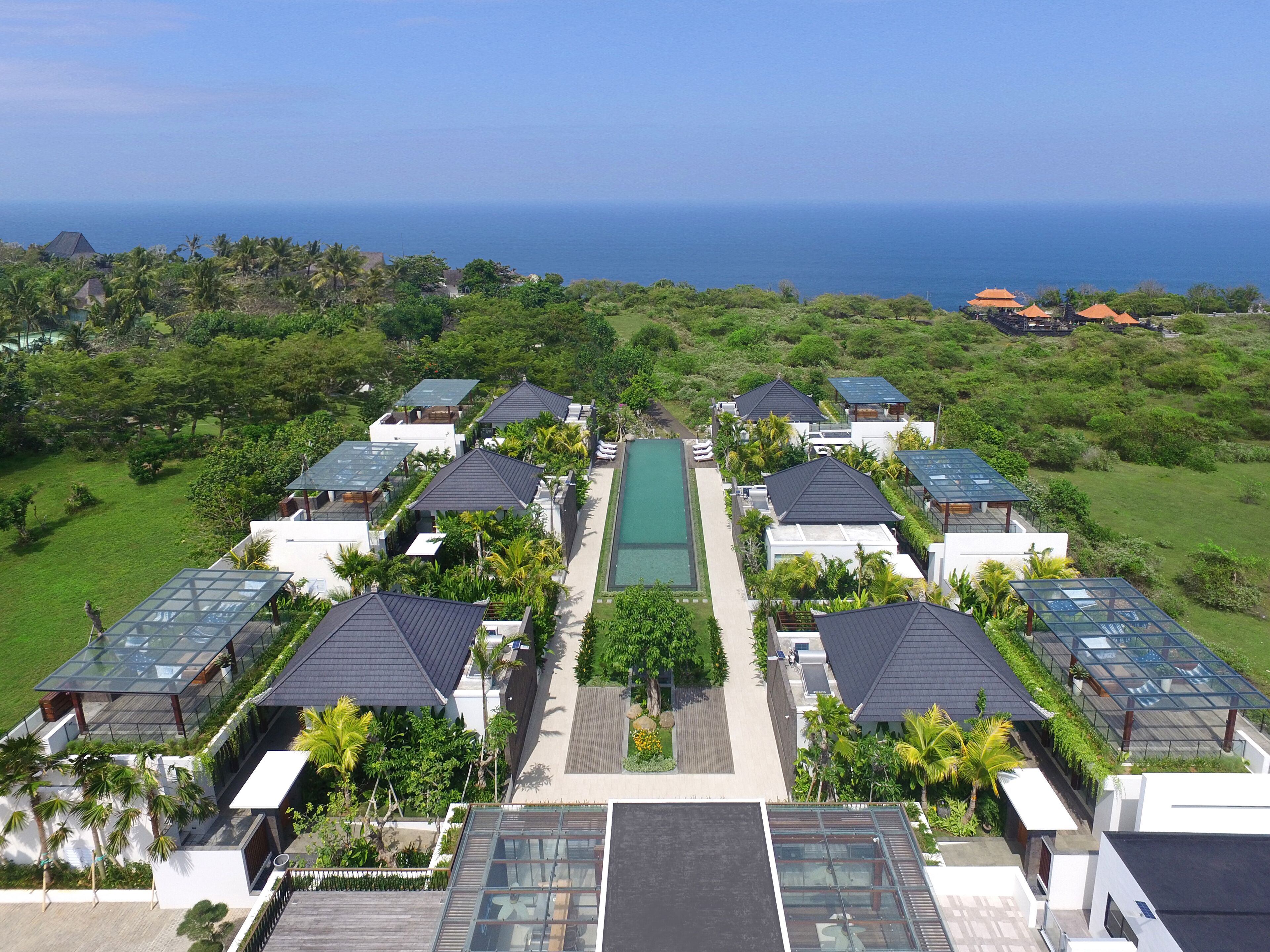 A resort with multiple buildings, a central pool, and a view of the ocean.
