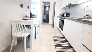 Una cocina moderna con armarios blancos, un comedor con sillas blancas y una alfombra a rayas.