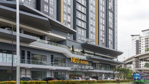 Un hotel moderno con varios pisos, balcones y un letrero llamativo que dice NEU SUITES.
