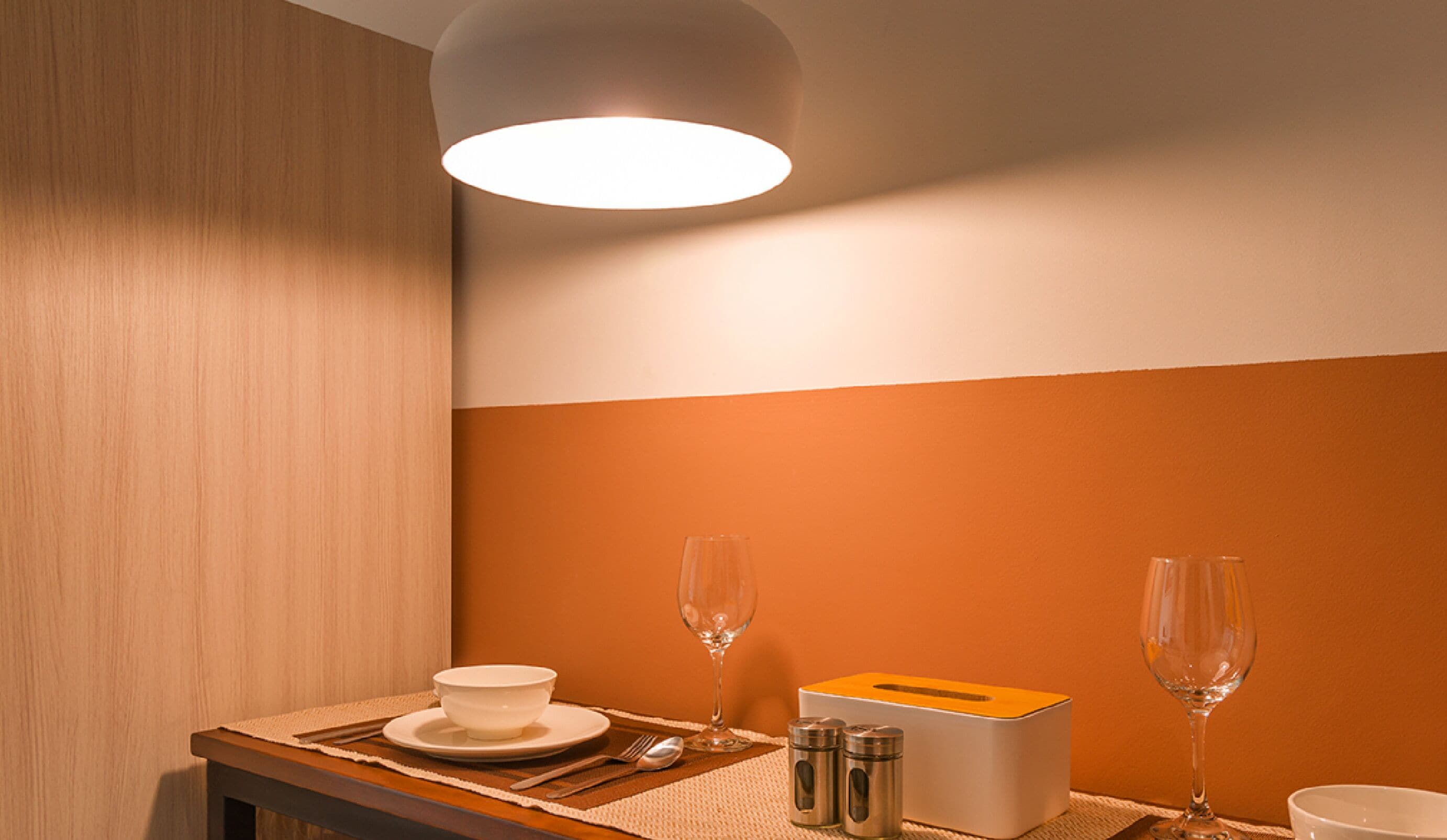 A neatly arranged dining area with a table set for two, including a bowl, wine glasses, cutlery, and a salt and pepper set.