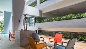 Un área de estar moderna al aire libre con varias sillas y una jardinera central.