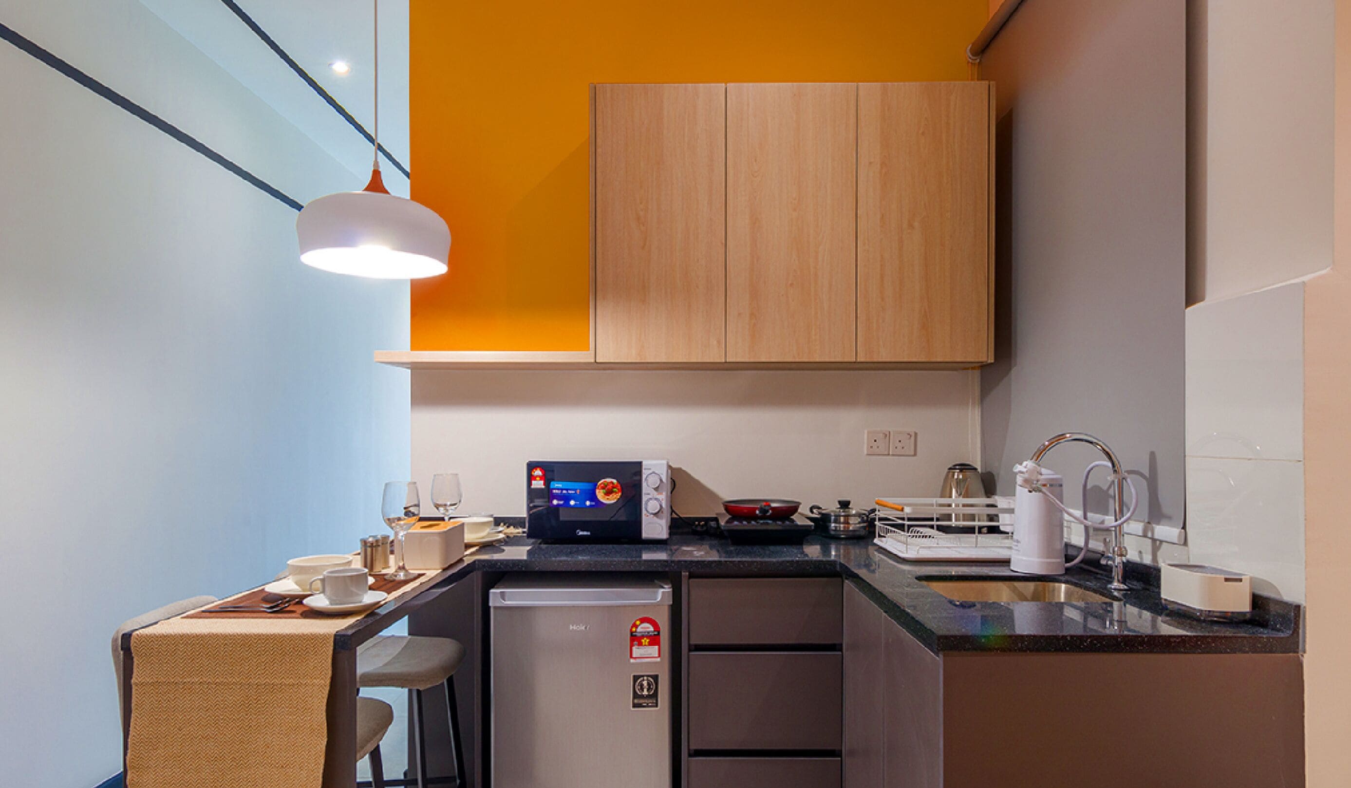 Une cuisine compacte équipée d’un four à micro-ondes, d’un grille-pain et d’un évier.