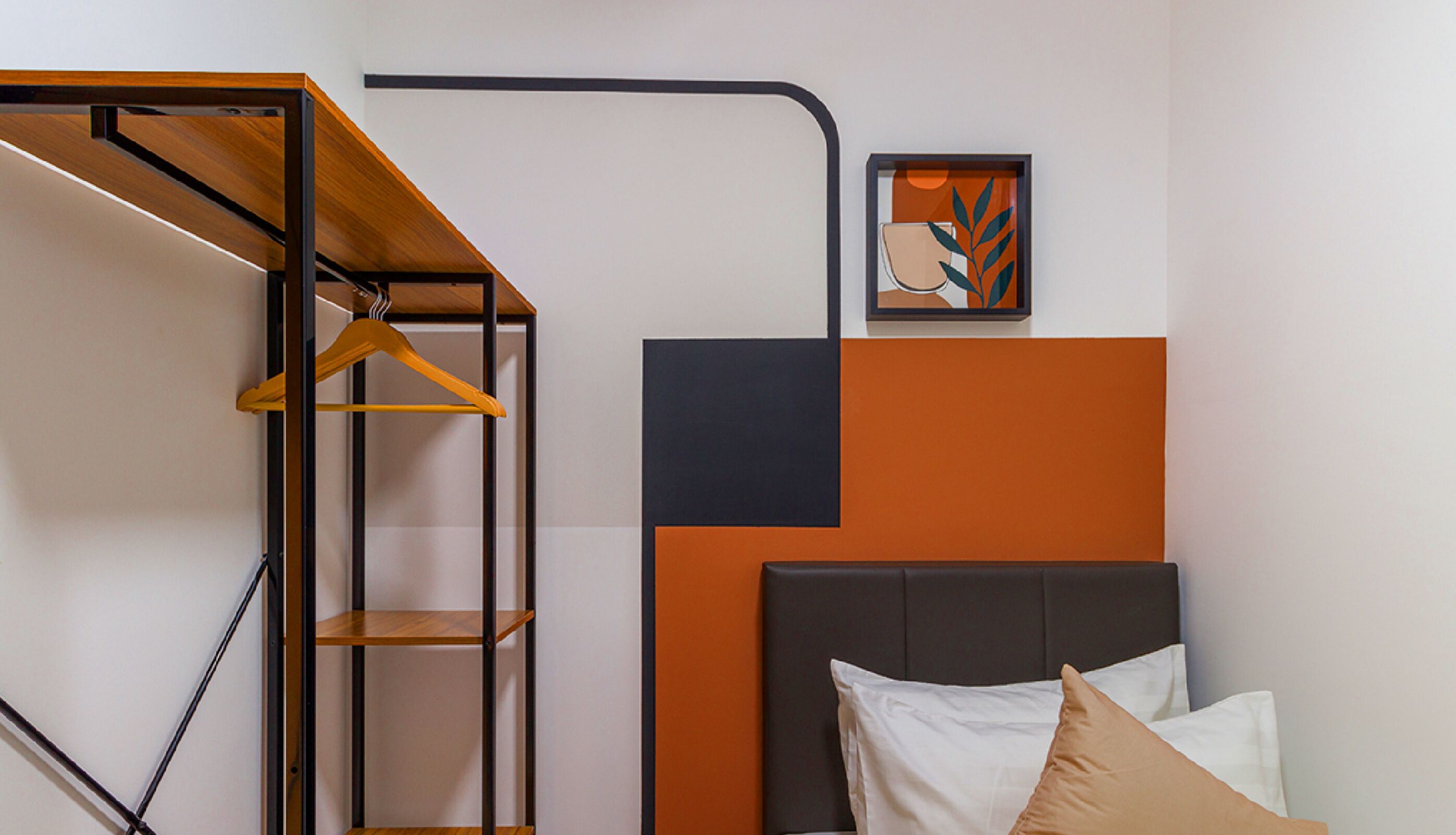 A bedroom with a bed, a hanging shelf, and a framed picture on the wall.