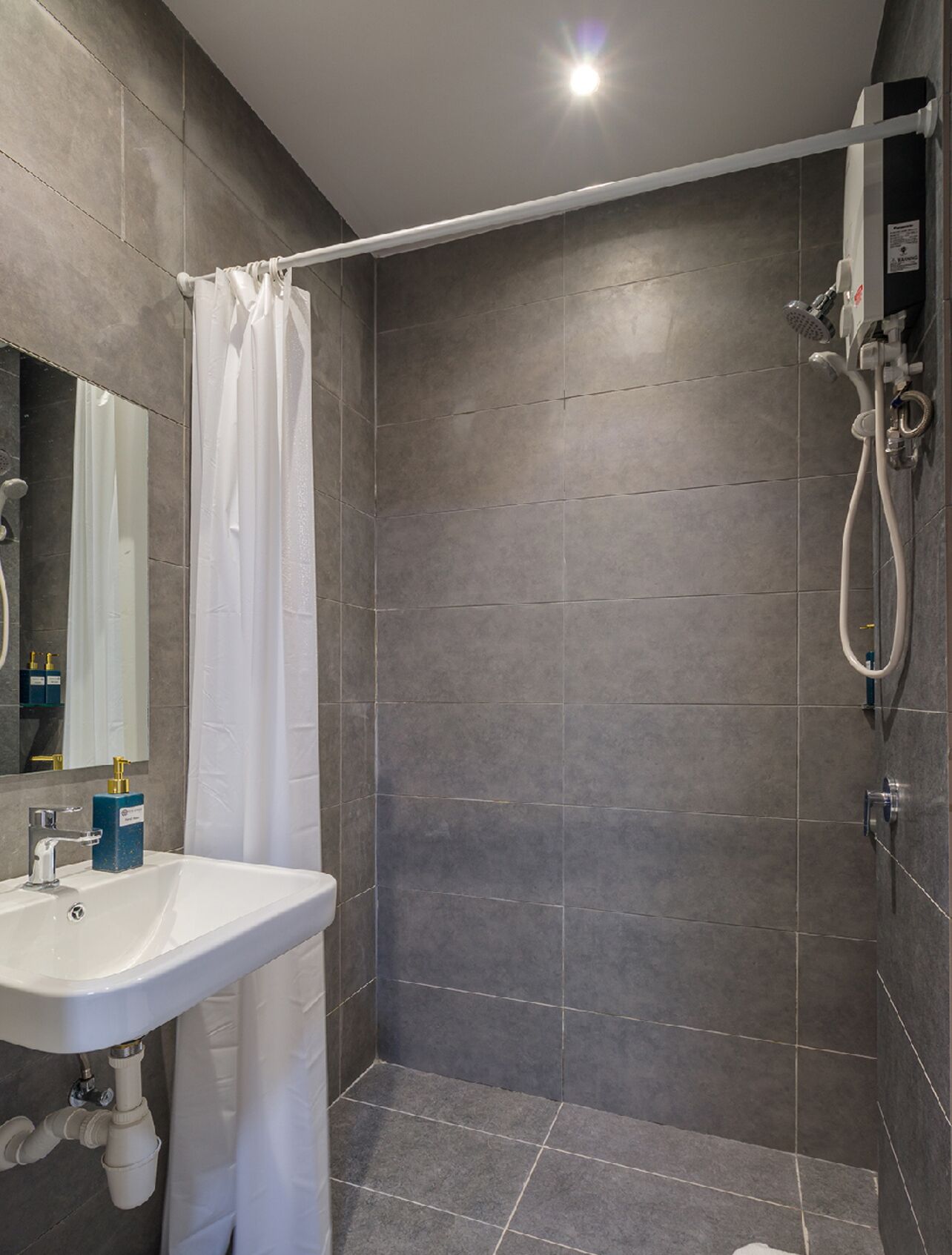 A modern bathroom with a shower, a sink, and a mirror.