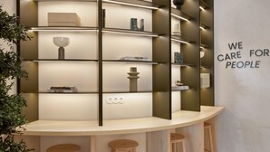 A modern interior with a curved counter, shelves with decorative items, and a 'WE CARE FOR PEOPLE' sign. - B&B Hotel Lleida (Lleida)
