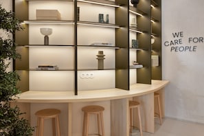 A modern interior with a curved counter, shelves with decorative items, and a 'WE CARE FOR PEOPLE' sign. - B&B Hotel Lleida  (Lleida)