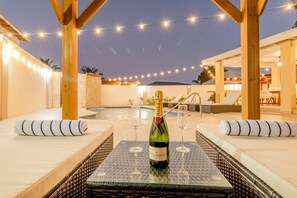 Un bar situé sur le toit d’un immeuble, avec une piscine, des chaises longues et une bouteille de champagne Moet & Chandon.