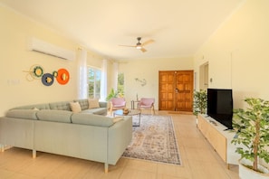 A living room with a sofa, chairs, a TV, and a wooden cabinet.