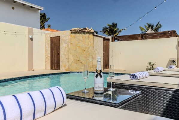 Un espace aménagé au bord de la piscine, avec une bouteille de champagne Moët & Chandon, deux verres et des serviettes sur une table.