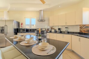 A modern kitchen with a central island, stainless steel appliances, and light-colored cabinetry.