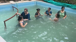 Un gruppo di persone in piscina, con una scaletta metallica.
