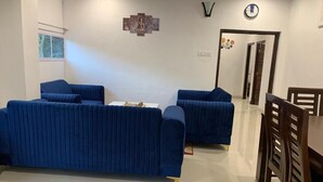 Un soggiorno con due divani blu, un tavolo da pranzo con sedie e una sveglia a muro.