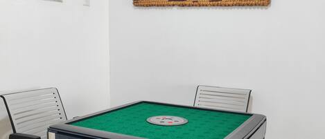 A room with a pool table, four chairs, and a decorative wall piece.