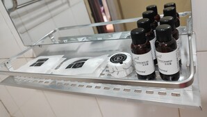 Une étagère de salle de bain contenant divers produits de toilette, notamment des flacons de shampoing et de gel douche, une brosse à dents et un rasoir.