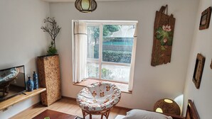 Une pièce confortable avec un lit, une chaise, un téléviseur et une fenêtre donnant sur un paysage verdoyant.