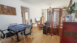 Un coin repas avec une table dressée pour deux personnes, un téléviseur et un paravent décoratif.