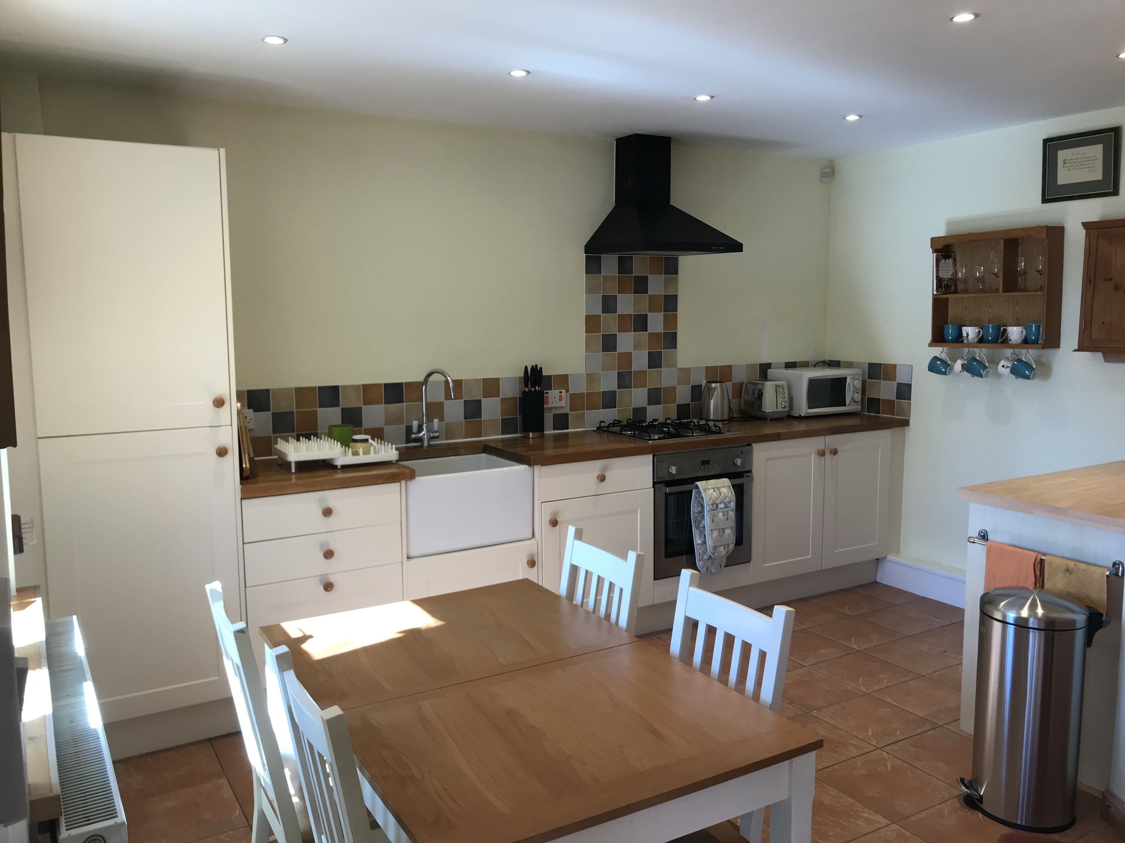 A modern kitchen with a wooden table, white chairs, a built-in oven, a microwave, and a gas stove.