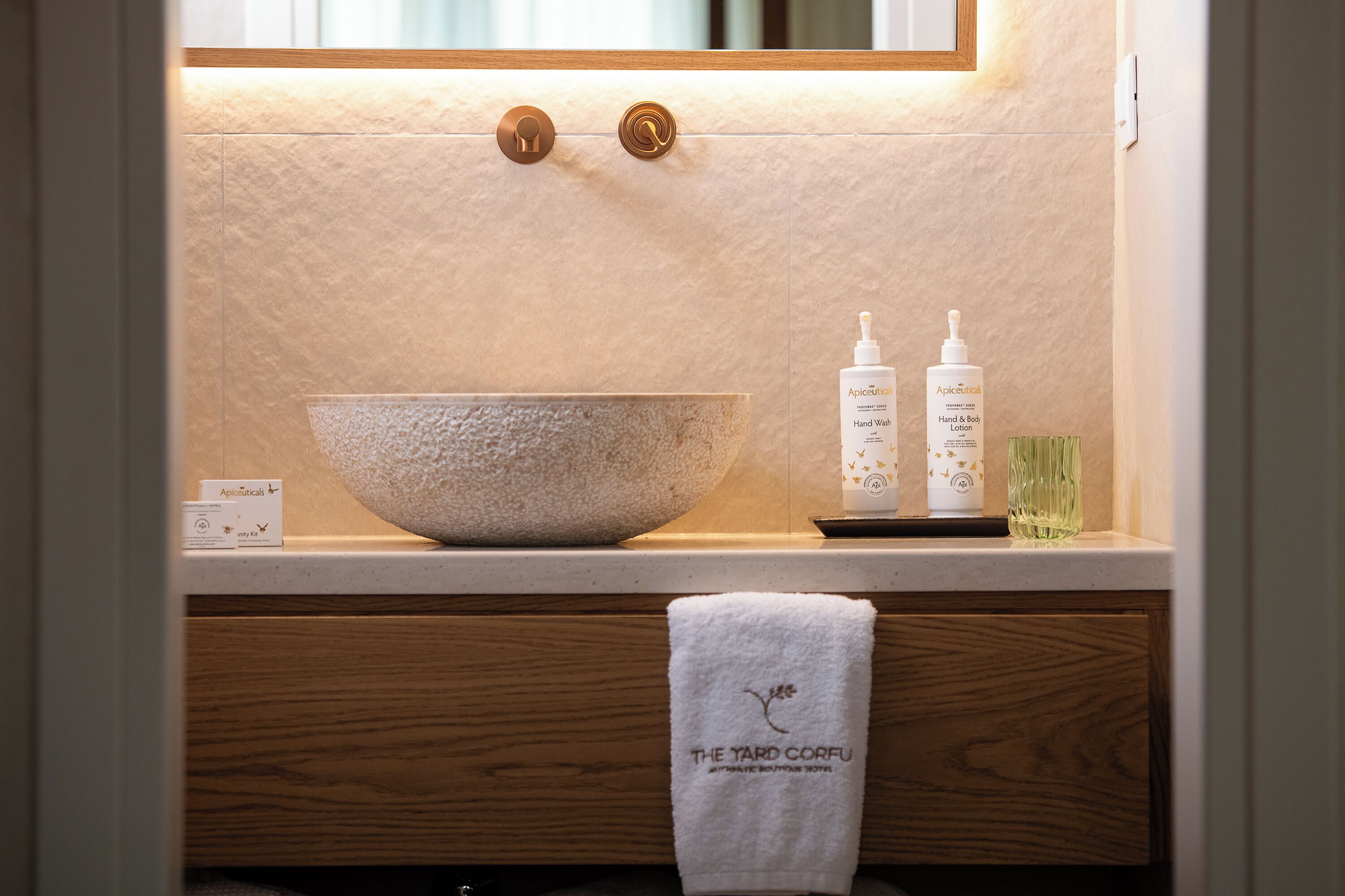 Un baño con un lavabo grande de piedra, dos botellas de loción corporal y una toalla con un logotipo.