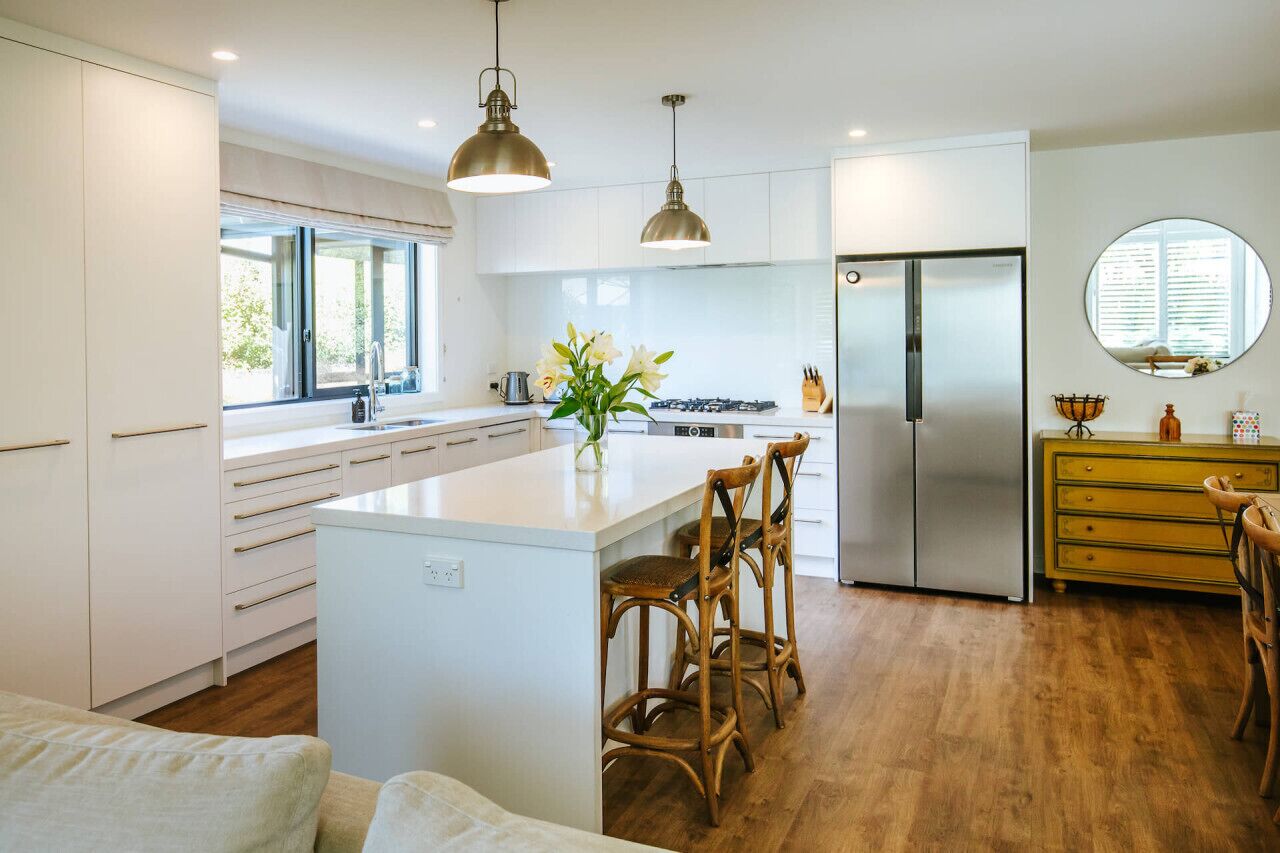 A modern kitchen with a central island, stainless steel appliances, and wooden flooring.