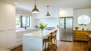 Een moderne keuken met een centraal eiland, roestvrijstalen apparatuur en houten vloeren.