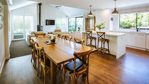 Een moderne keuken met een groot eiland, een houten eettafel en stoelen.