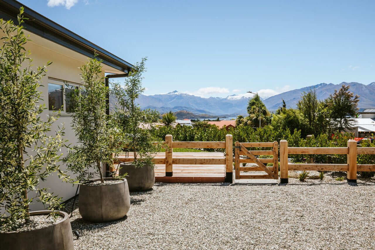 A building with a gravel driveway, wooden gate, and potted plants.